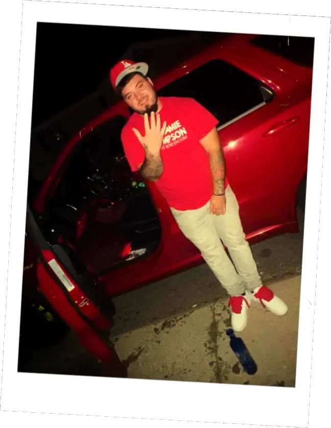 Jackson in a Jamie Thompson campaign shirt beside a red car